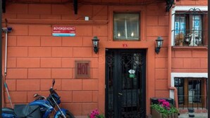 Un edificio con fachada roja, puerta negra y un letrero que indica un restaurante.
