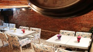 Un comedor rústico con paredes de ladrillo y mobiliario estampado con motivos florales.