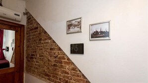 Una escalera con un muro de ladrillo en un lado y un muro blanco en el otro, con dos cuadros enmarcados en el muro blanco.