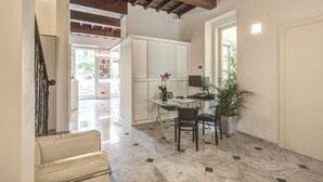 Una habitación amplia con suelo de mármol, un escritorio con computadora, una silla y una planta en maceta.
