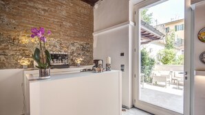 Una cocina moderna con pared de ladrillo, encimera blanca y vista al patio exterior.
