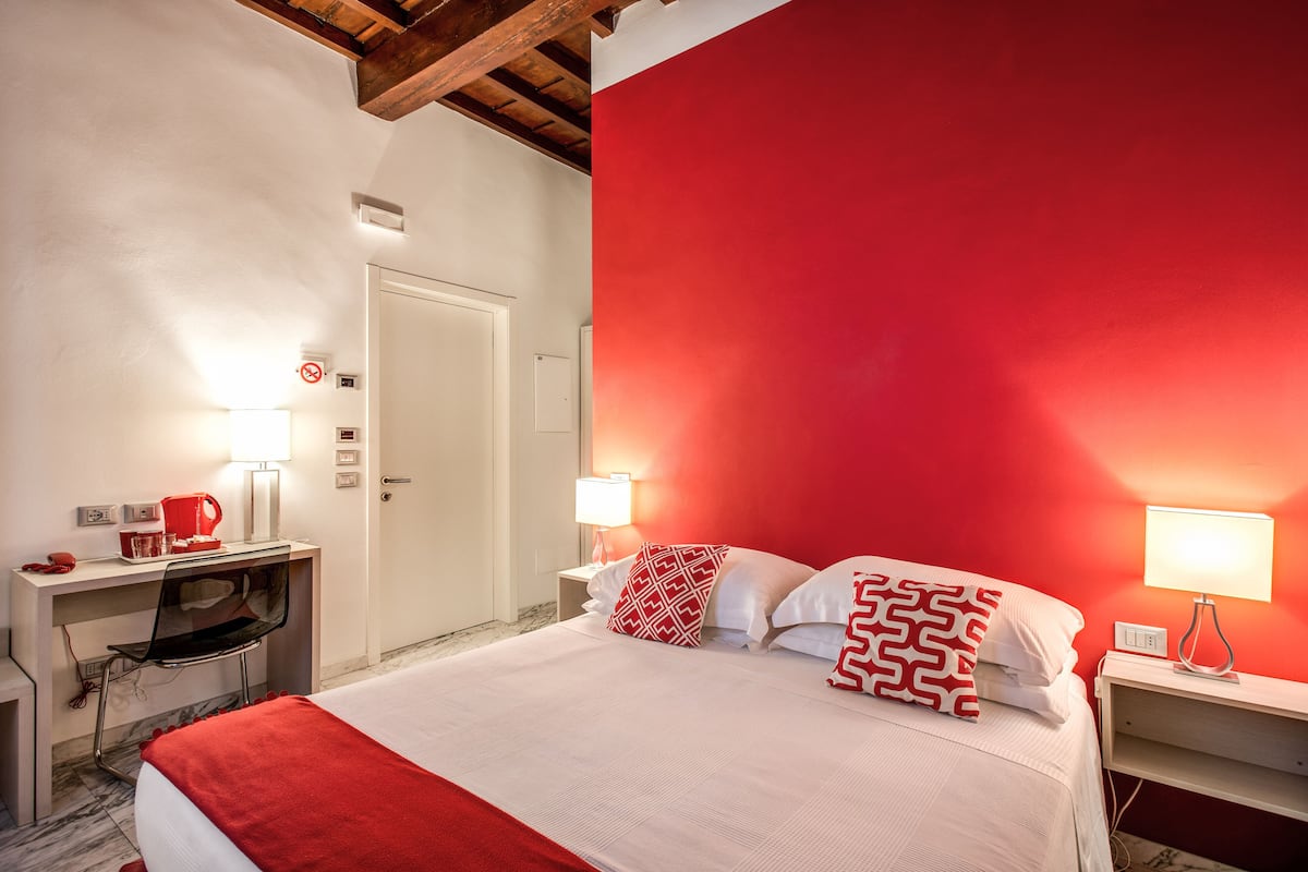 A hotel room with a bed, desk, chair, and two bedside lamps.