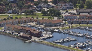 A marina with boats docked, surrounded by residential buildings and a grassy area. - Hotel Rudkøbing Skudehavn (Rudkobing)
