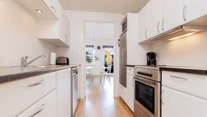A modern kitchen with white cabinetry, stainless steel appliances, and a wooden floor. - Hotel Rudkøbing Skudehavn (Rudkobing)