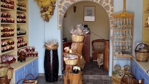 A rustic interior with shelves of jars, baskets, and a stone archway. - Akti Rooms (Astypalaia)