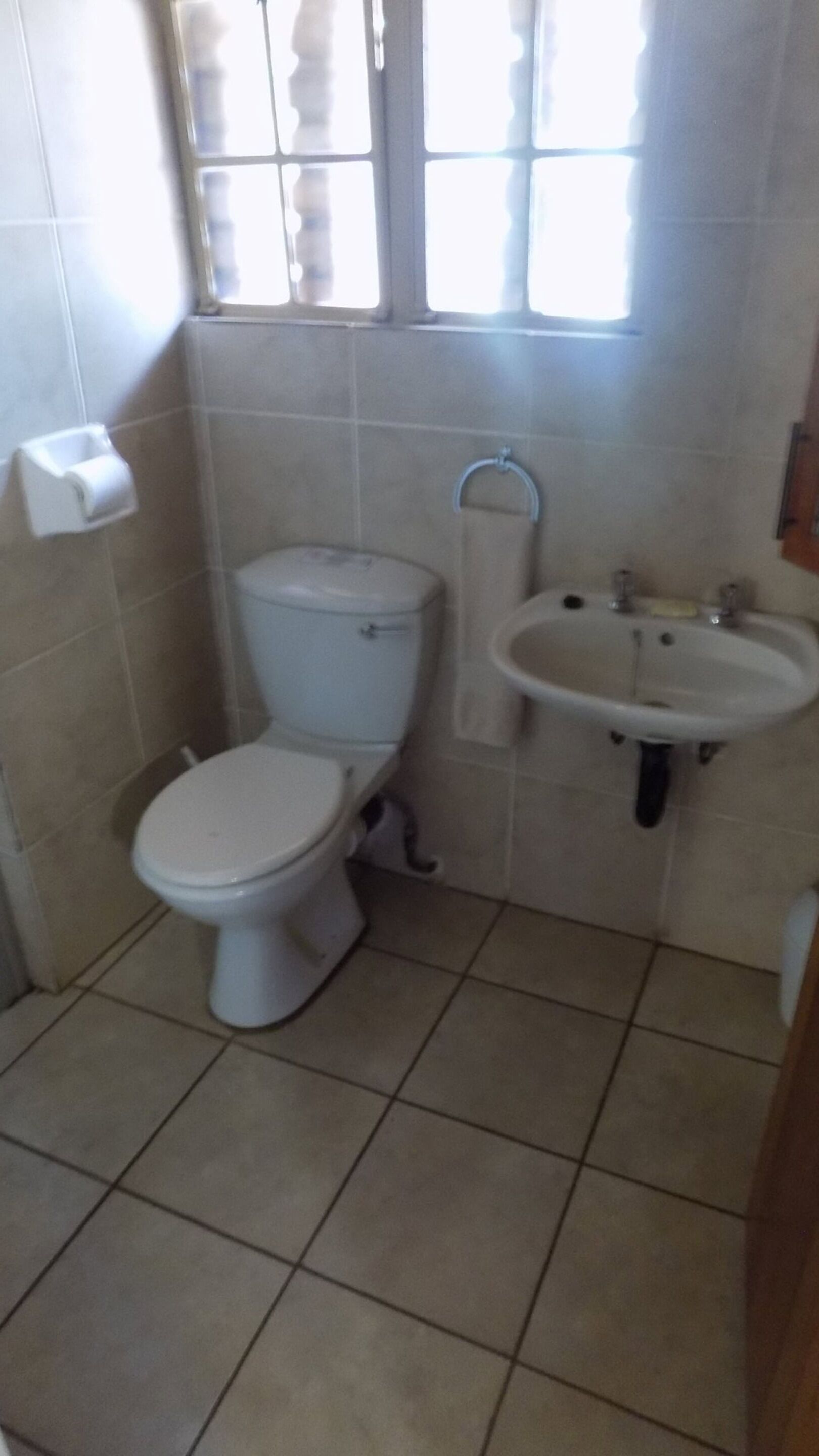 A small bathroom with a toilet, sink, and window.