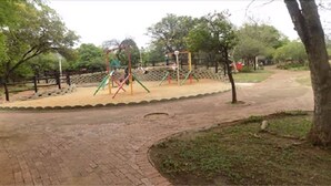 Un sendero pavimentado que lleva a un parque infantil con columpios y un tobogán.