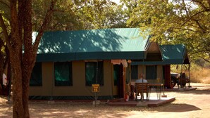 Una tienda safari con techo verde, un cartel que indica que es la tienda número 15, y una mesa con sillas afuera.