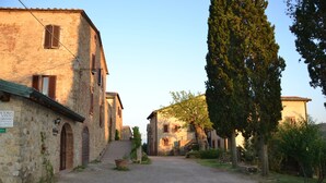 A narrow cobblestone street flanked by historic stone buildings with arched doorways and wooden shutters. - Fattoria Il Santo (Monticiano)