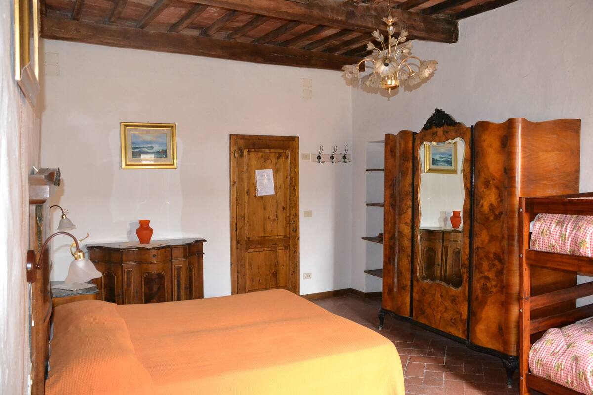 Een slaapkamer met een houten bed, een kaptafel, een spiegel en een kroonluchter.