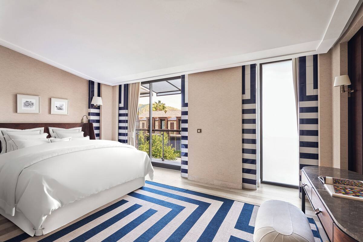 Une chambre d’hôtel avec un grand lit, un bureau et une vue sur un immeuble par la fenêtre.