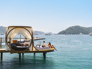 A floating deck with a canopy, a table with chairs, and a lounge chair.