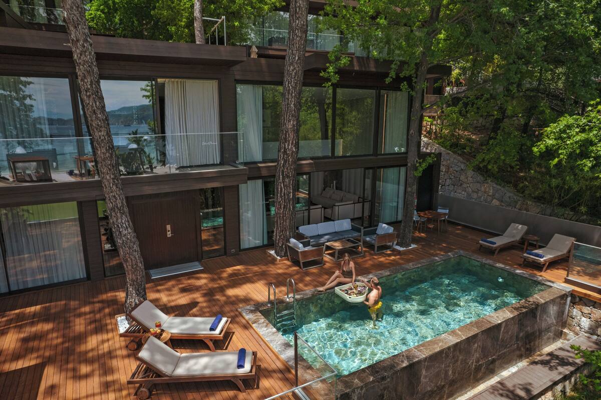 Une villa moderne dotée d’un balcon entièrement vitré, d’une piscine et d’un espace salon extérieur.