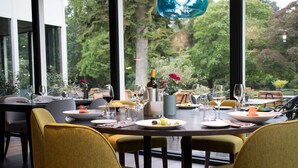 Comedor con una mesa preparada para dos personas, sillas alrededor y vista a zonas verdes.