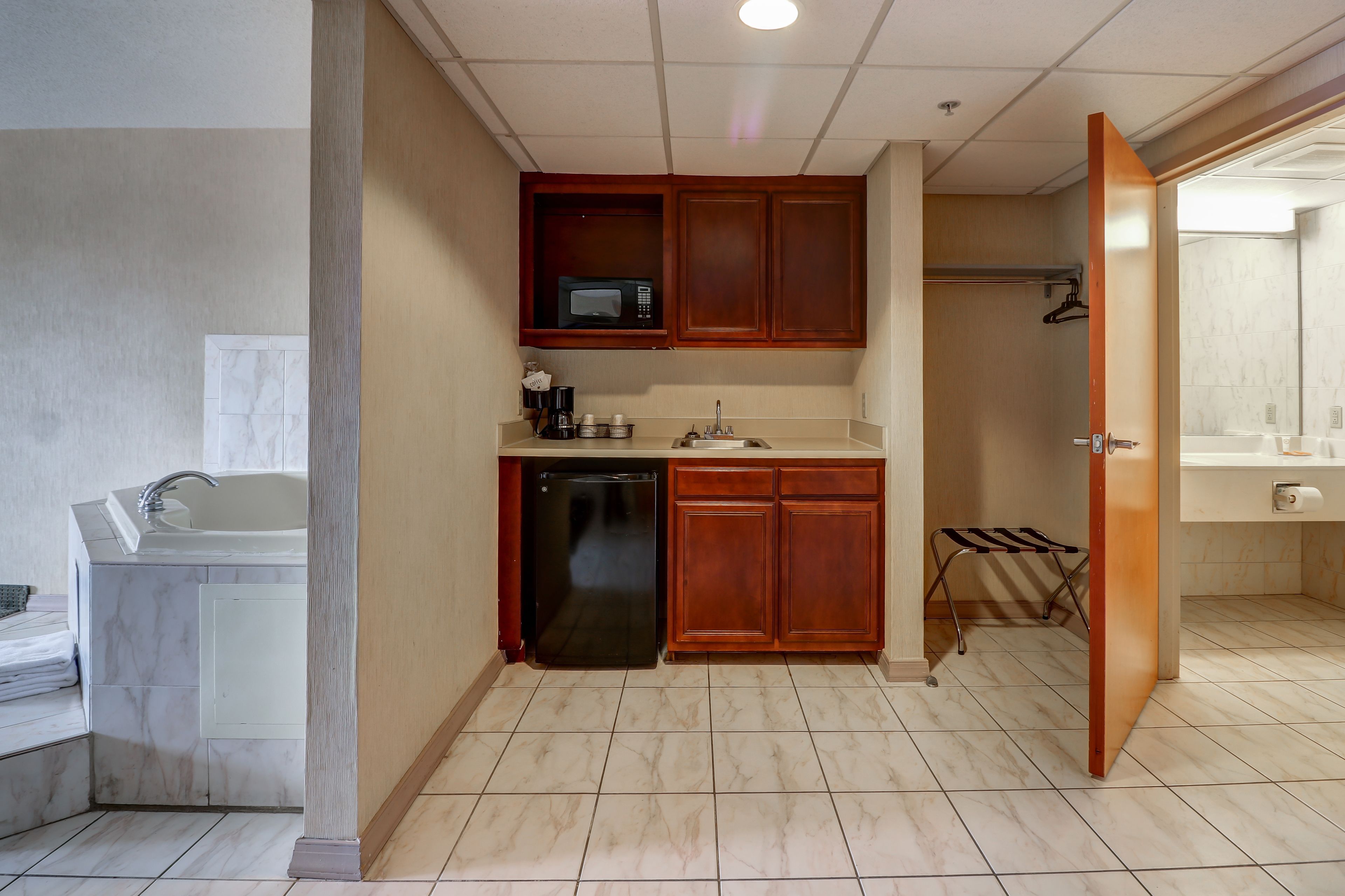 A compact kitchen with a microwave, sink, and dishwasher, wooden cabinets, and a towel rack.
