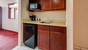 Una cocina compacta con armarios de madera, microondas integrado, fregadero y lavavajillas.