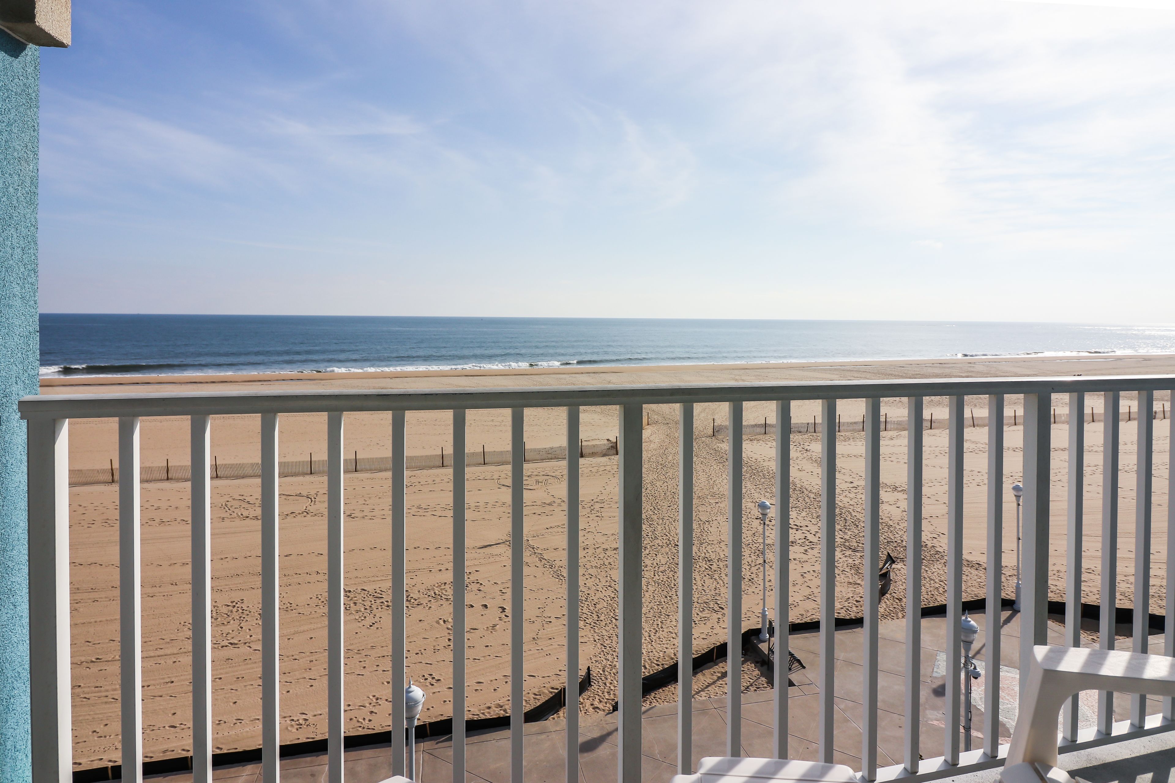 A balcony with a view of a sandy beach and the ocean.