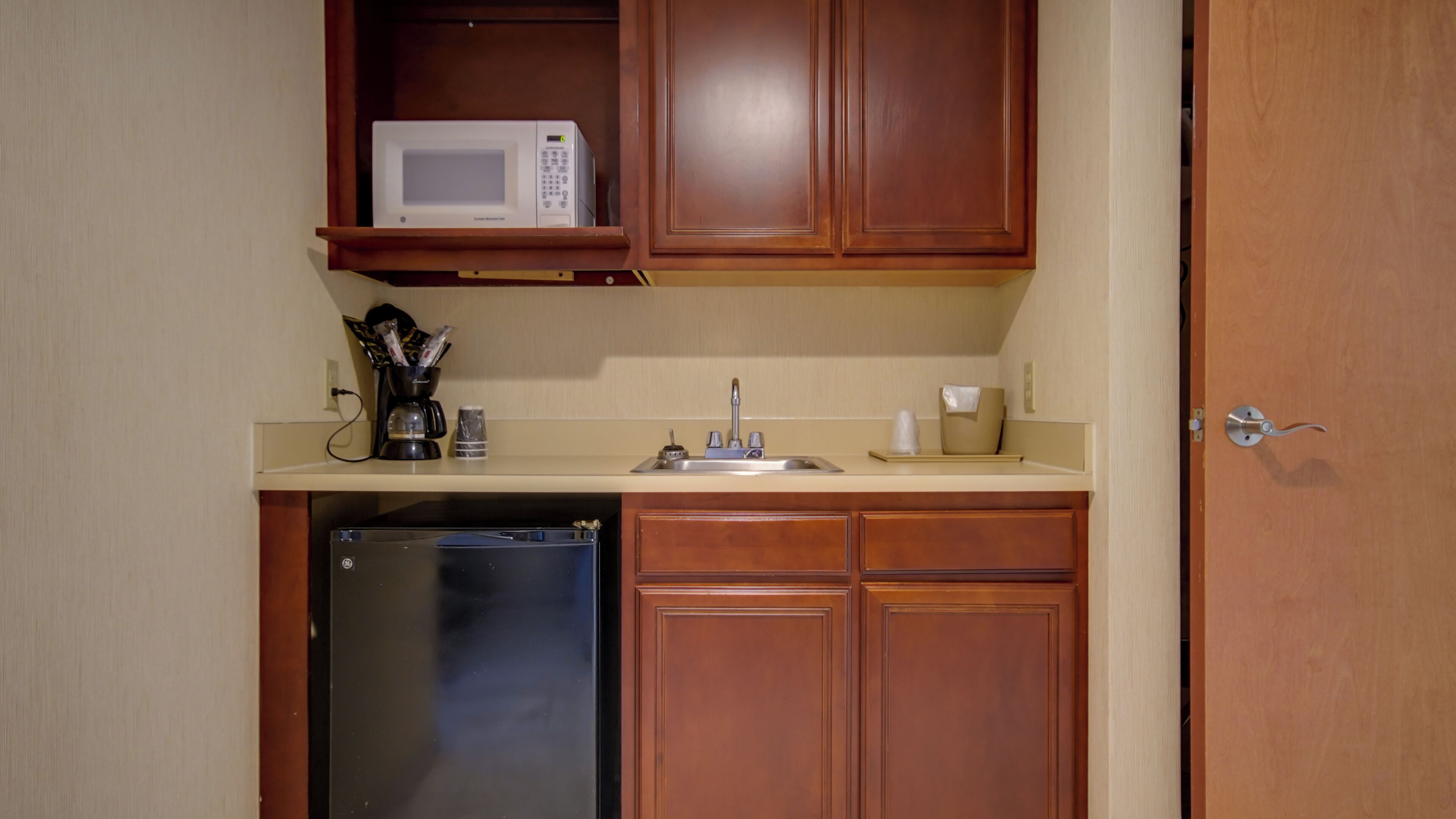 A compact kitchenette with a microwave, coffee maker, and a refrigerator.