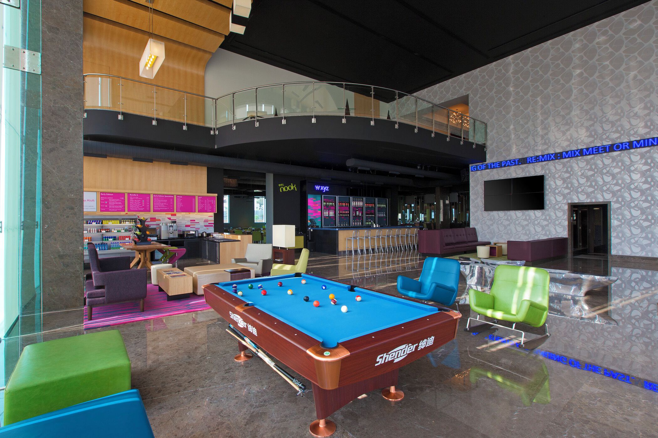 Une table de billard dans un espace intérieur moderne, avec des sièges et un coin bar.