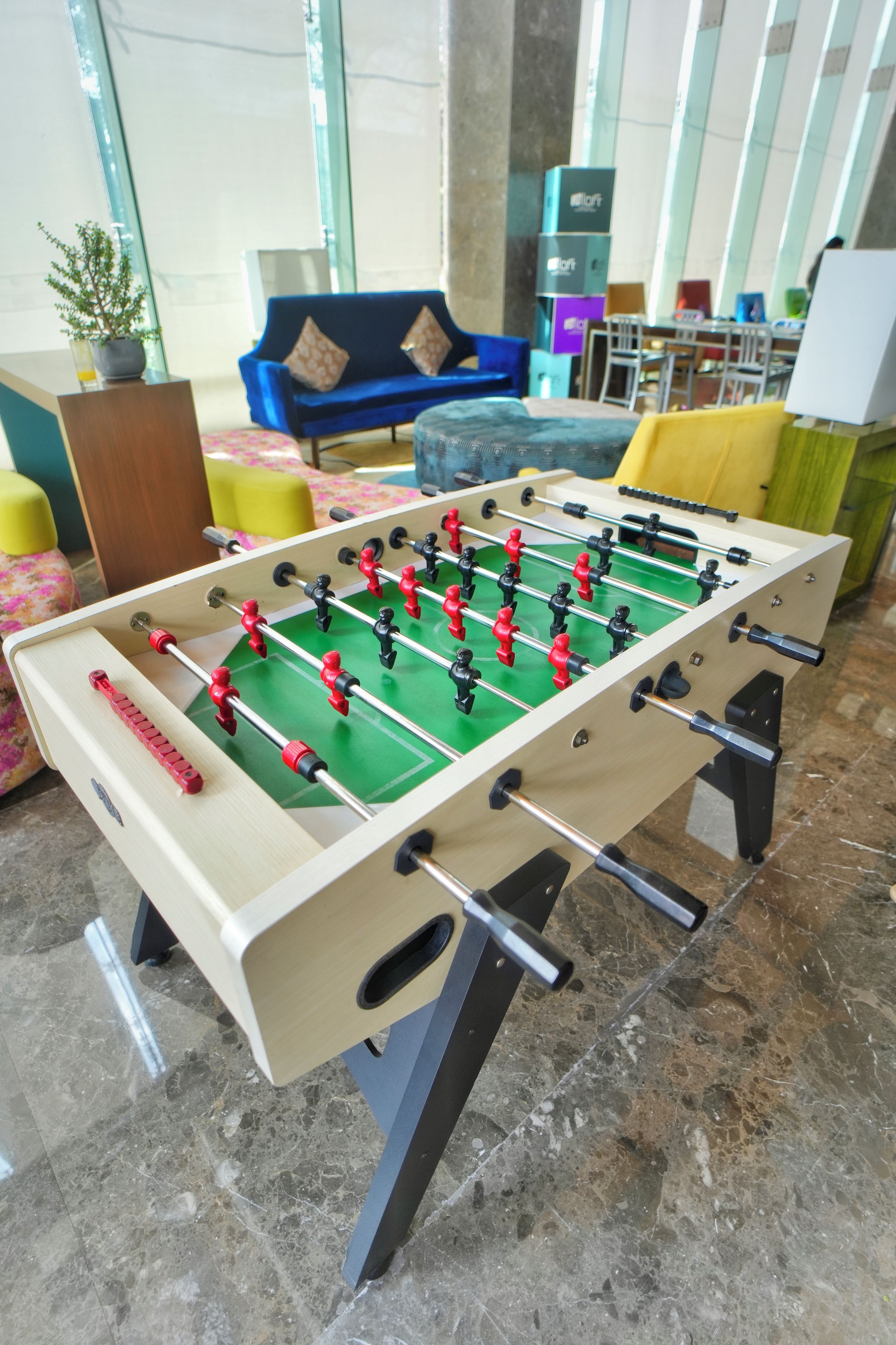 Une table de baby-foot dans une pièce où se trouvent un canapé, des fauteuils et une table basse.