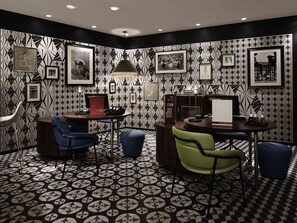 A modern room with geometric patterned wallpaper, a round table with chairs, and framed artwork on the walls.