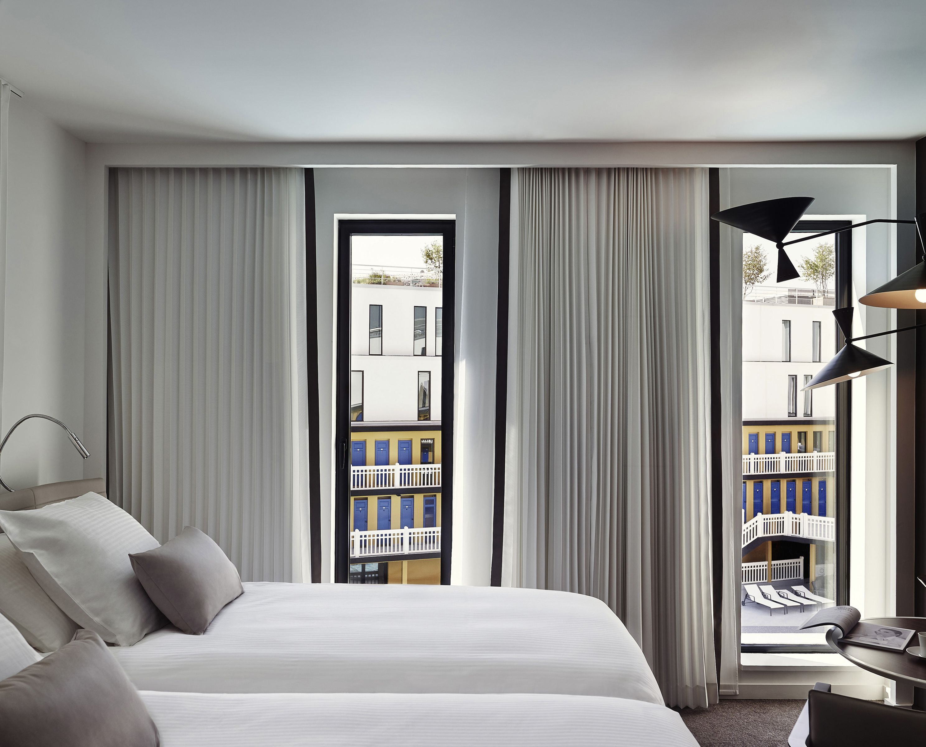 Une chambre d’hôtel avec un grand lit, un bureau et une vue sur un immeuble doté de balcons.