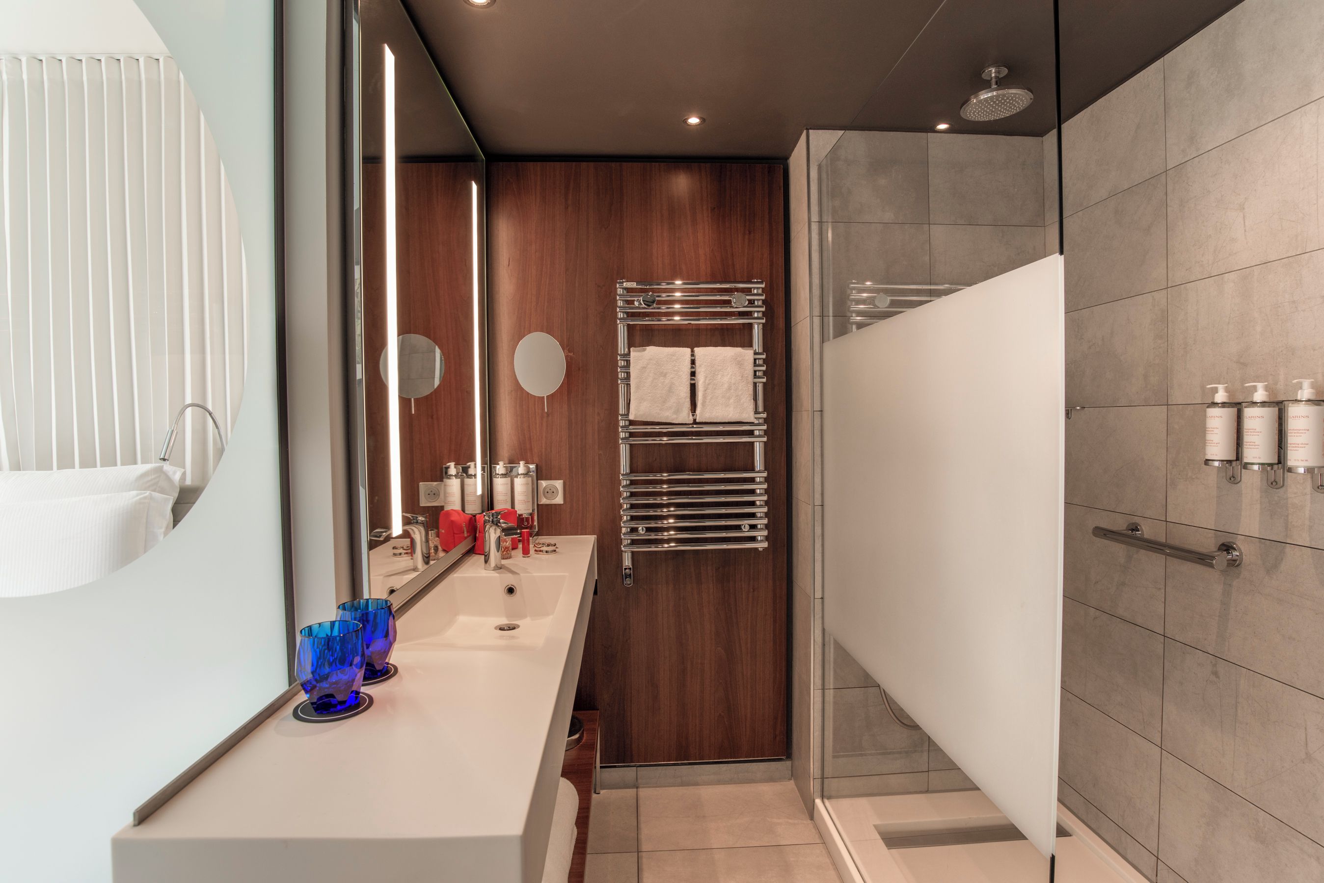A modern bathroom with a shower, a vanity with a mirror, and a towel rack.