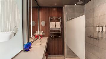 A modern bathroom with a shower, a vanity with a mirror, and a towel rack.