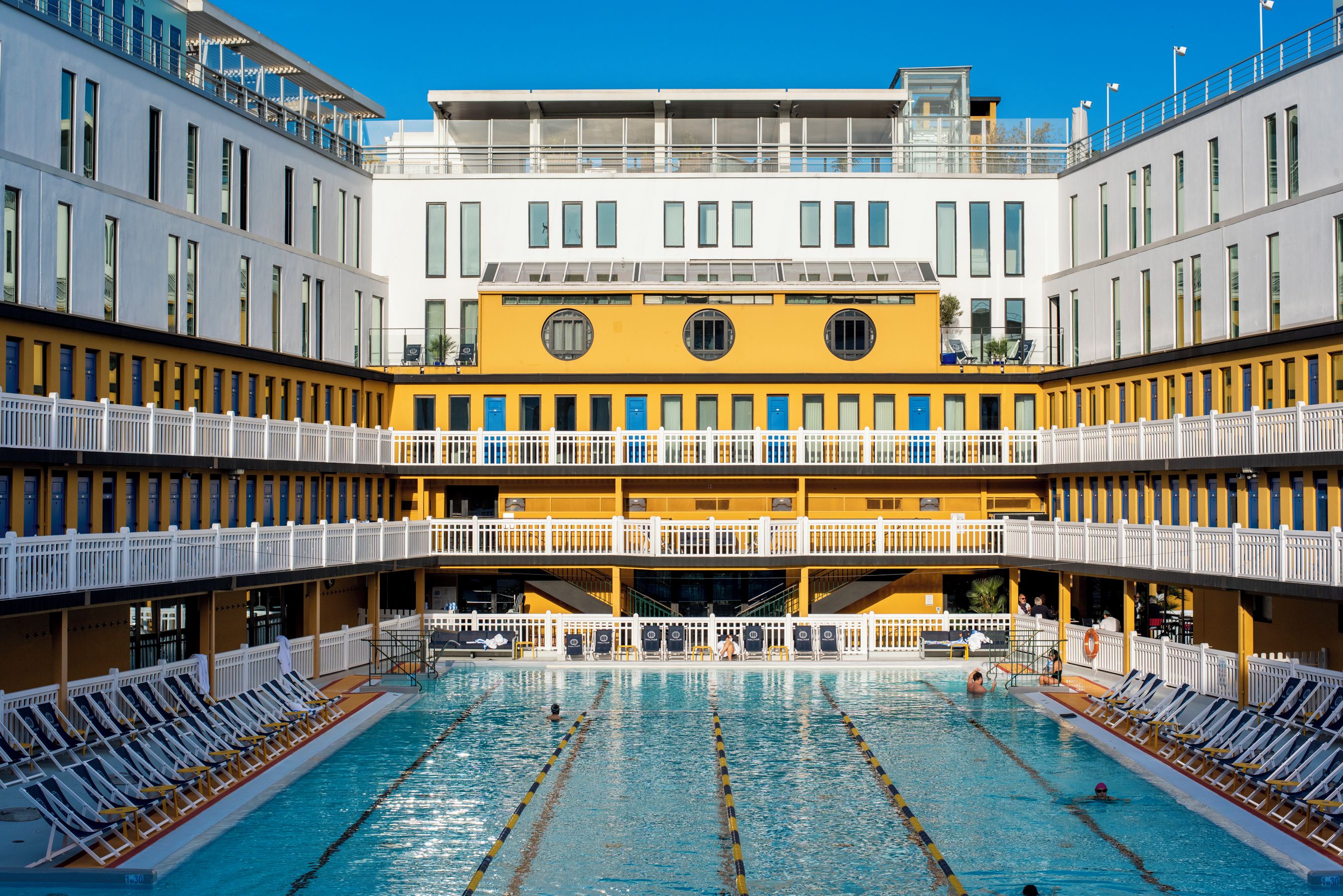 Un hotel de varios niveles con una piscina central rodeada de tumbonas.