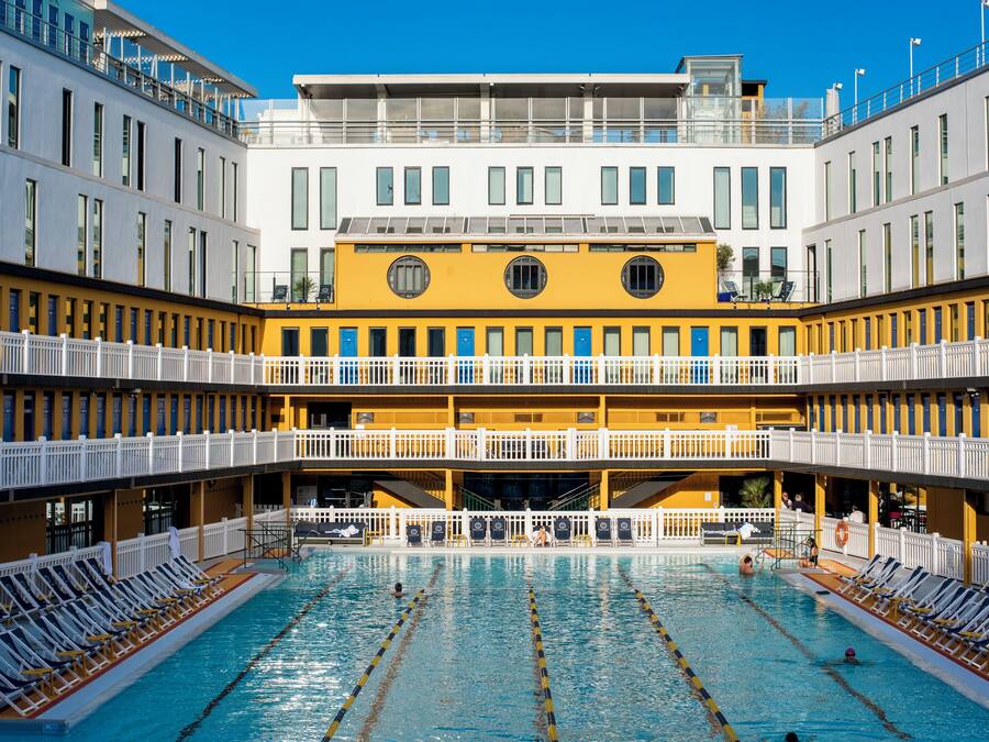 Un hotel de varios niveles con una piscina central rodeada de tumbonas.