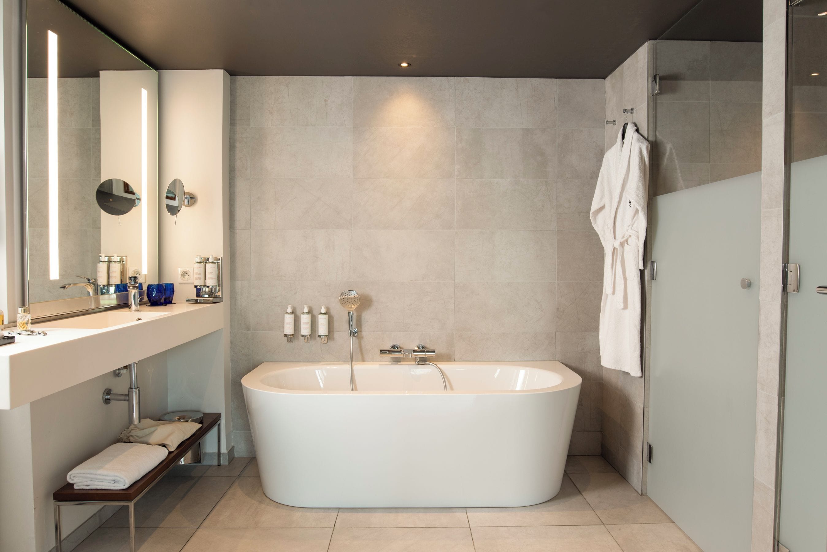 A modern bathroom with a freestanding bathtub, a vanity with a mirror, and a glass shower enclosure.