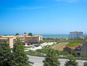 A coastal hotel with multiple buildings, a road, and greenery.