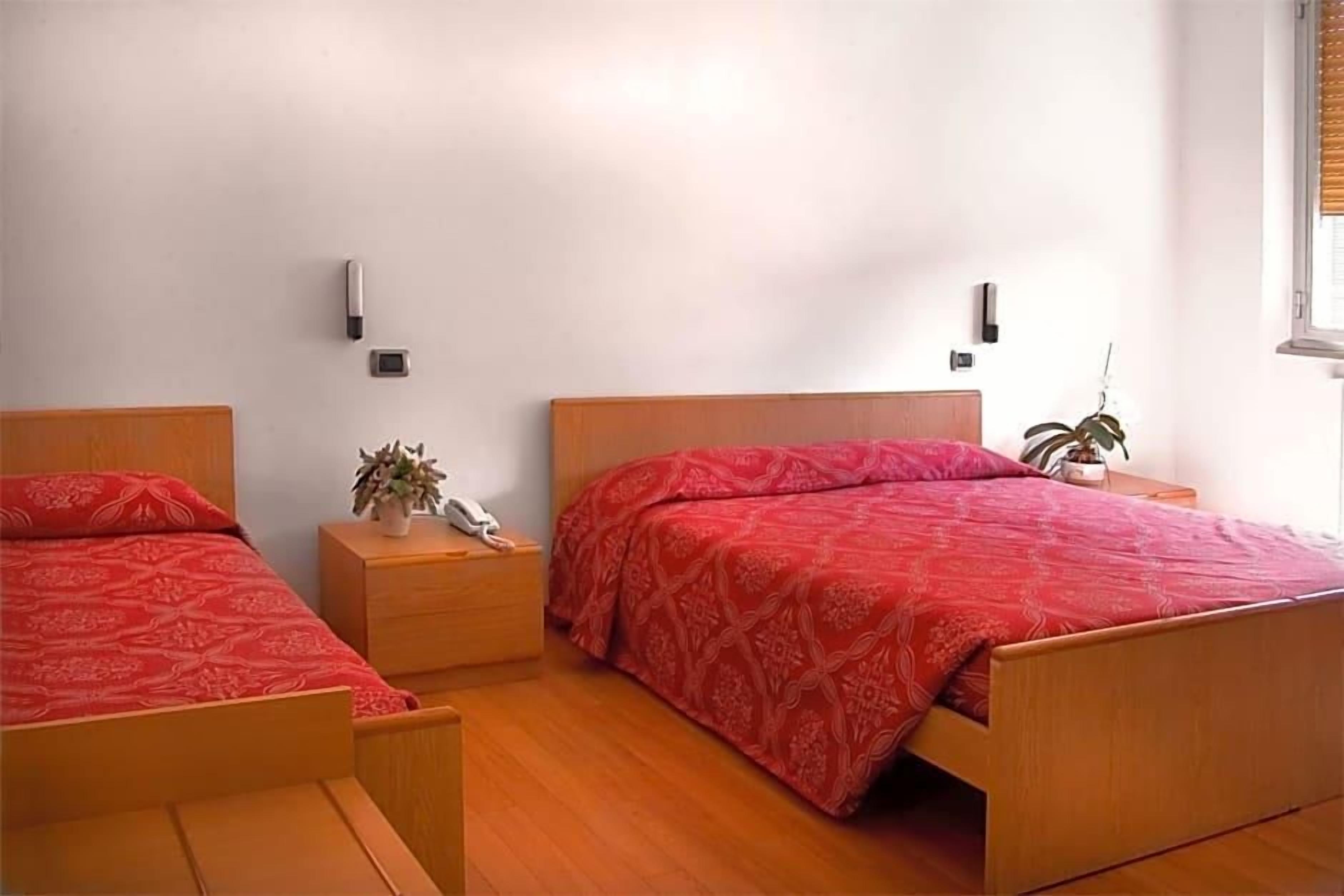 Une chambre à coucher avec deux lits en bois, une table de chevet avec une lampe et un téléphone fixé au mur.