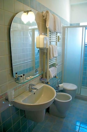 A bathroom with a sink, two toilets, a mirror, and a towel rack.