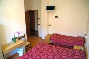 Une chambre avec deux lits, un bureau, une chaise, une télévision et une porte donnant sur une autre pièce.
