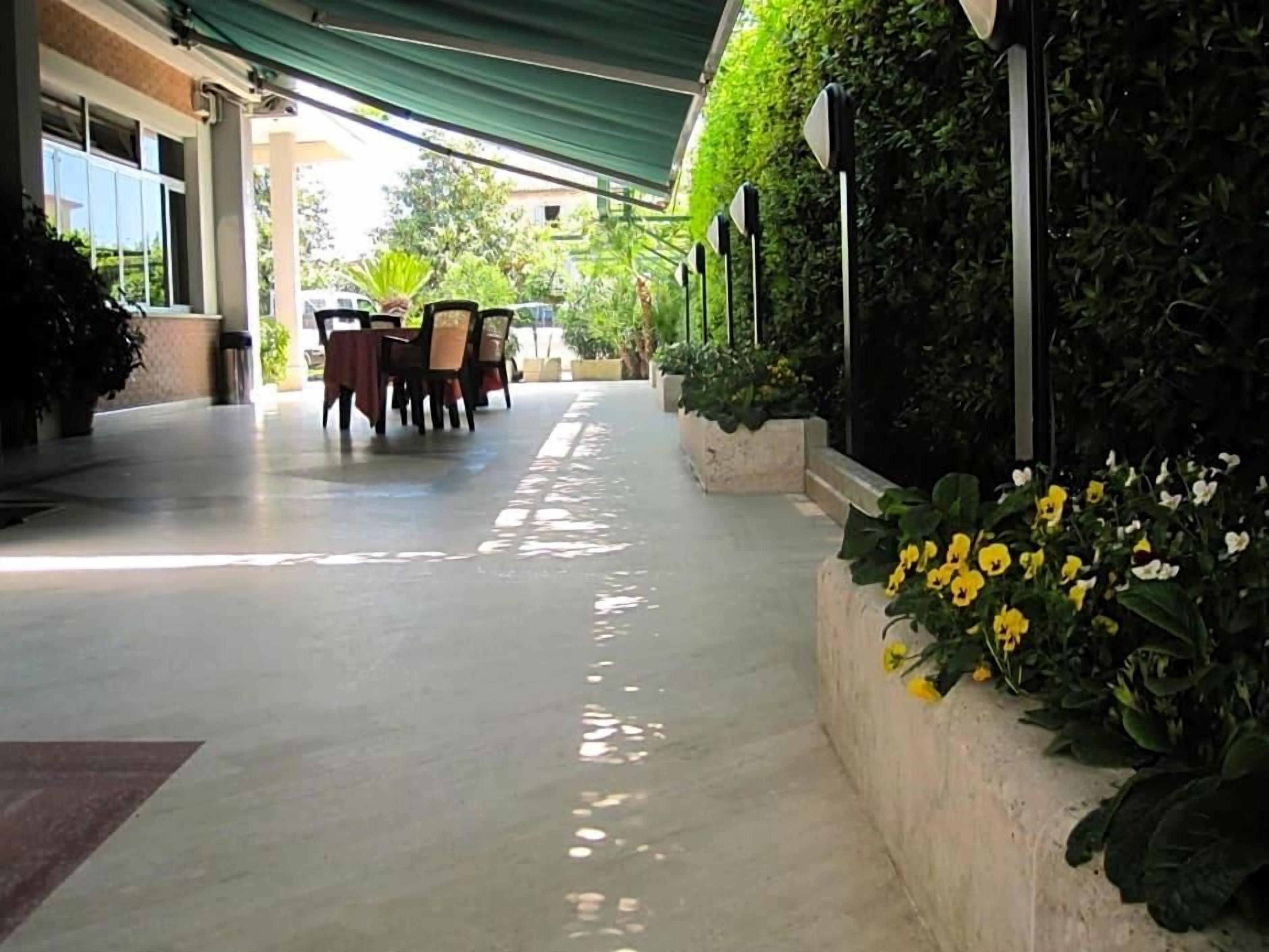 Uma área externa coberta com disposição para sentar e um jardim com flores amarelas.