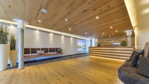 A spacious lobby with a wooden ceiling, a seating area with cushions, and a staircase leading to an upper level. - Hotel Schiller (Olching)
