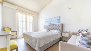 A bedroom with a large bed, a desk, and a chair. - Hotel Agia Markella (Chios)