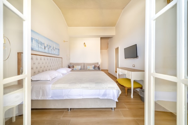 Un dormitorio con una cama grande, un escritorio, una silla y un televisor.