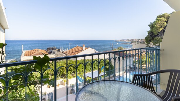 A balcony with a clear view of the sea, a pool, and surrounding greenery. - Hotel Agia Markella (Chios)