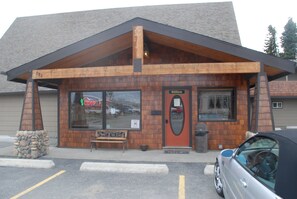 A building with a wooden facade, a sign reading "Office," and a bench outside.