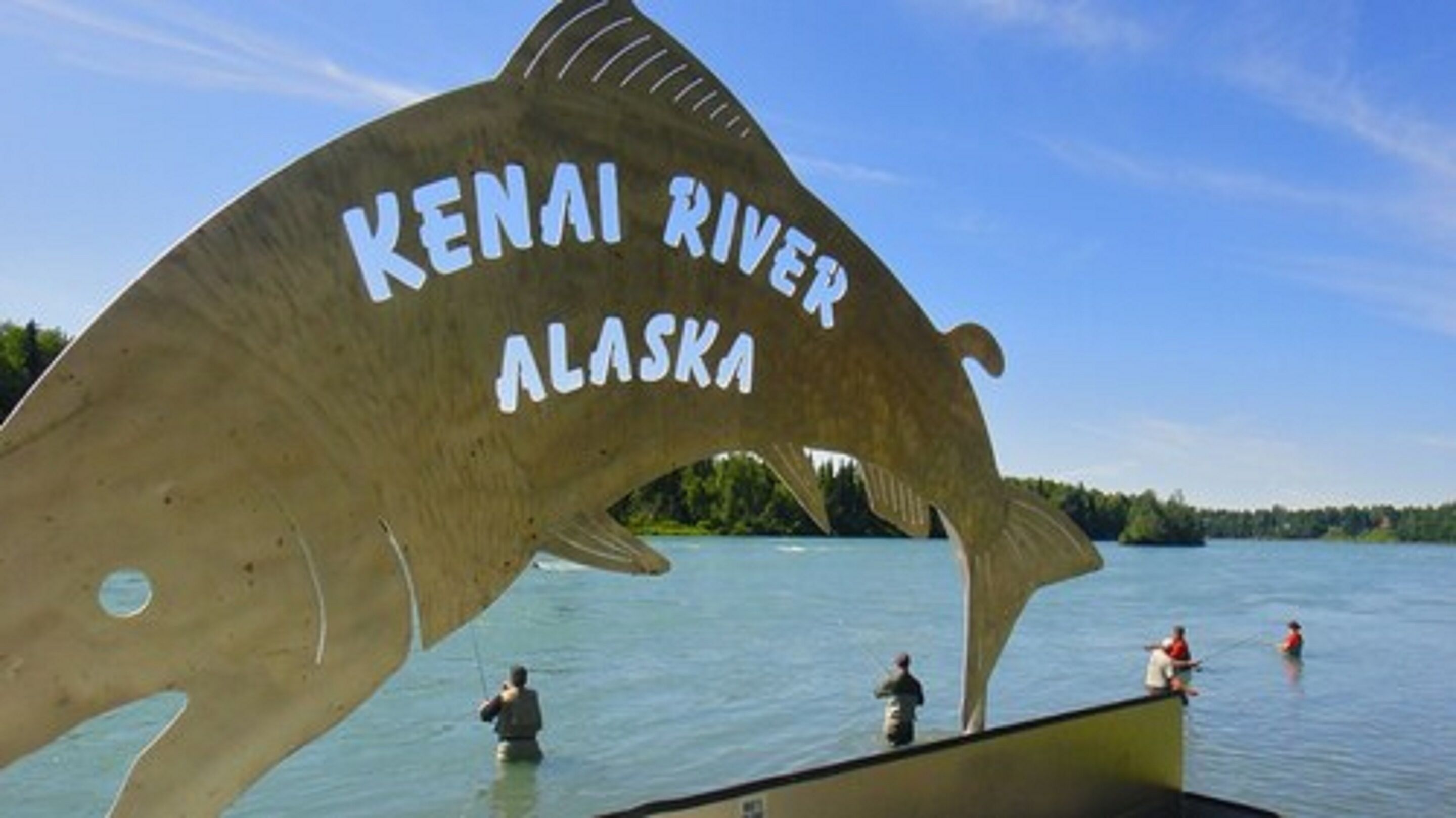 A large whale sculpture with the text "KENAI RIVER ALASKA" on a body of water with people in boats.