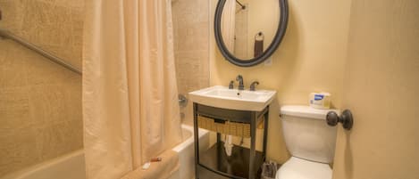 A bathroom with a bathtub, toilet, sink, and a mirror.