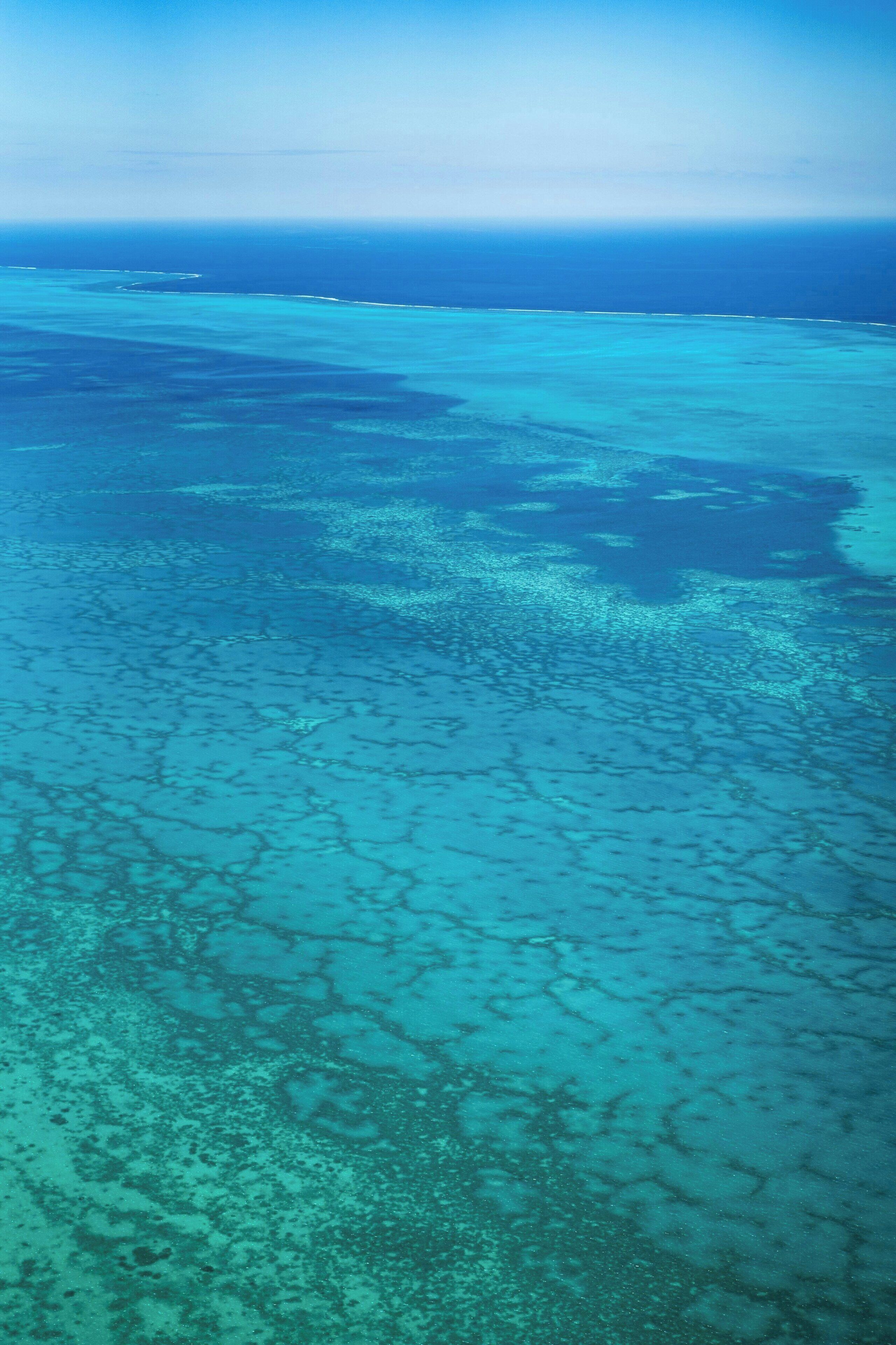 An aerial view of a coastal area with clear blue waters and visible landmasses.