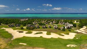 A coastal resort with thatched-roof cottages, a golf course, and a view of the turquoise sea. - Le Domaine Deva, Series by Marriott (Bourail)