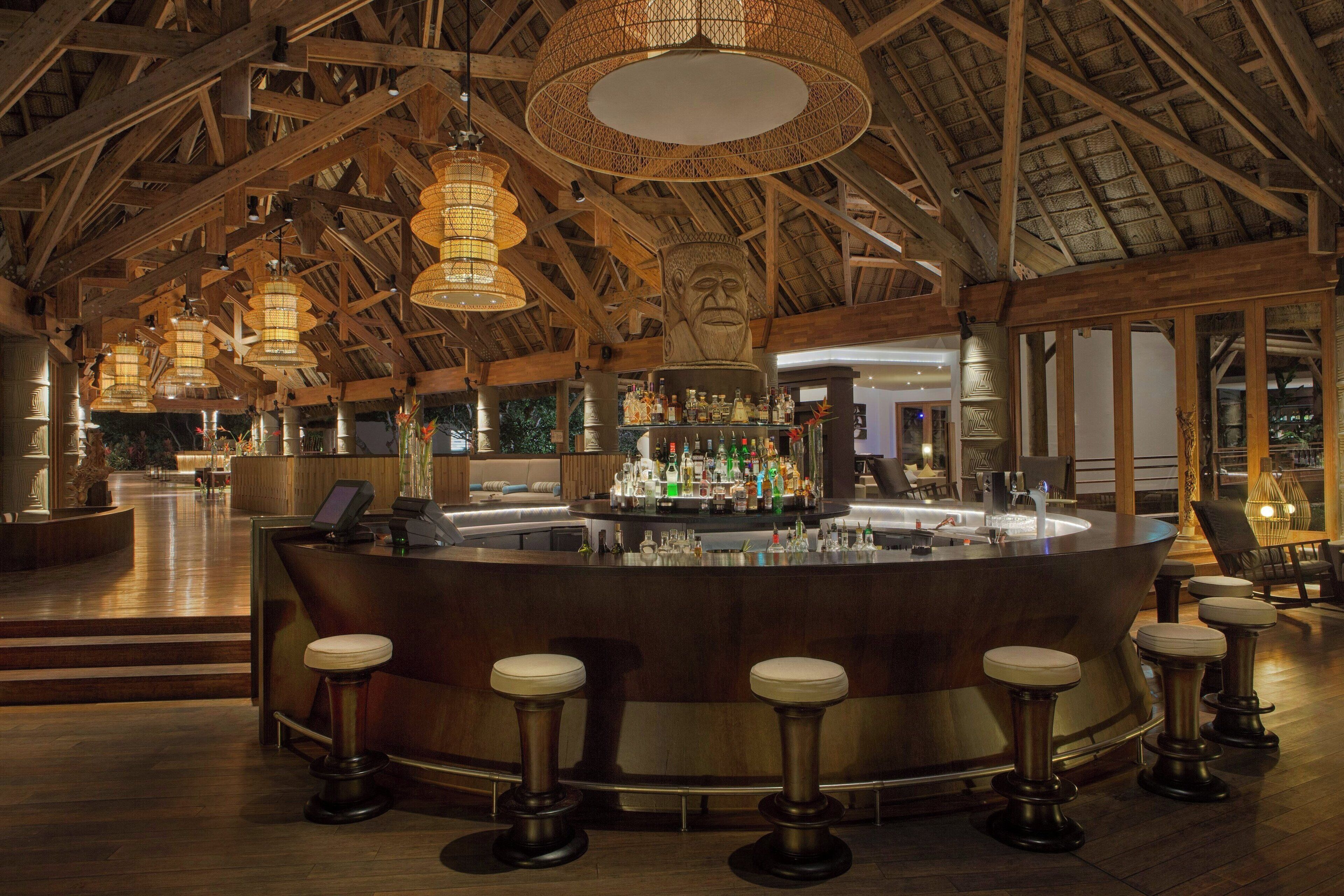 A bar area with a wooden ceiling, bar stools, and a bar counter.