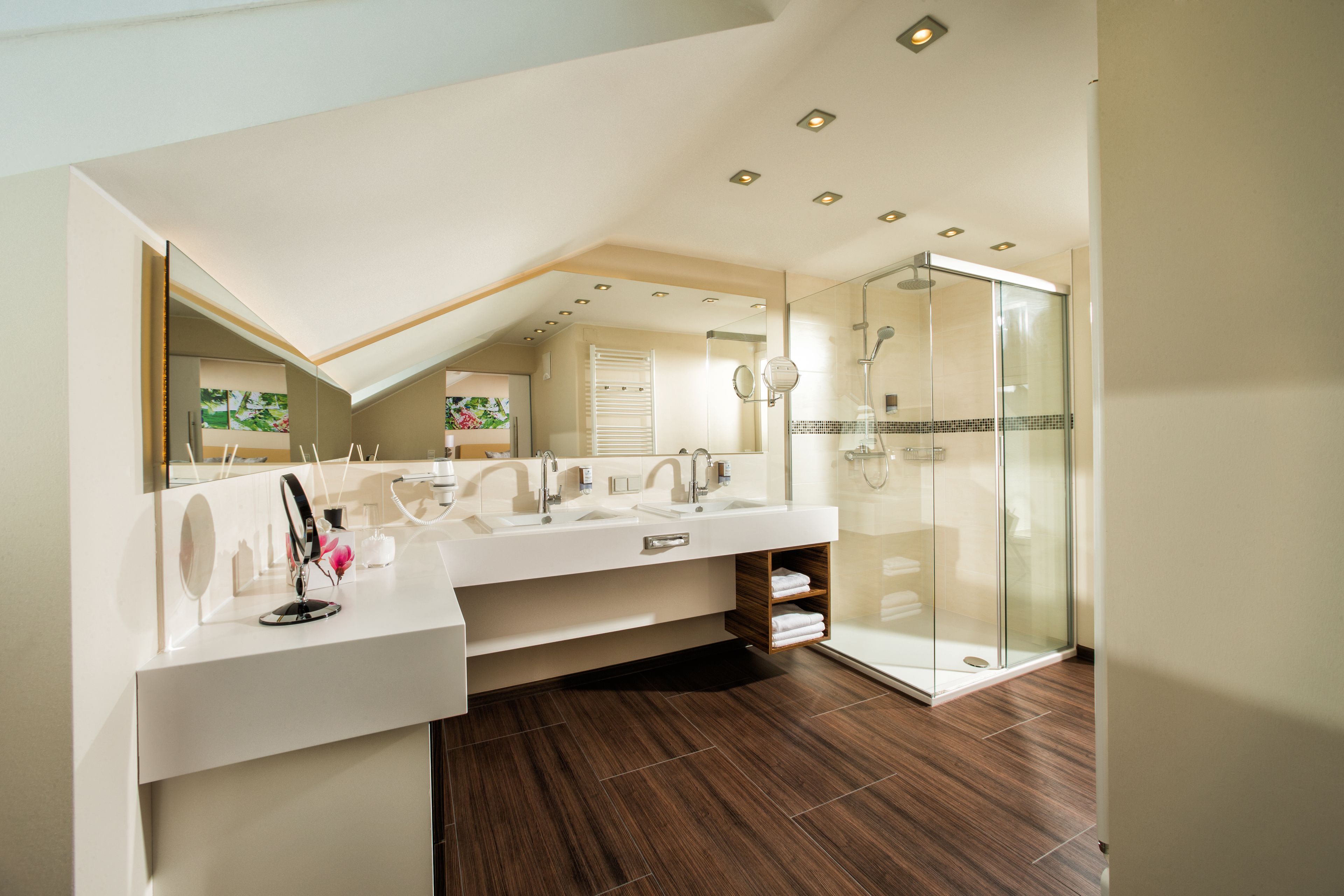 Un baño moderno con un lavamanos espacioso, cabina de ducha de vidrio y tragaluz.