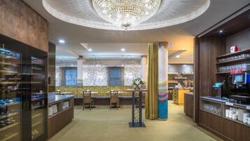 Een hotellobby met een centraal zitgedeelte, een kroonluchter en een receptiebalie.