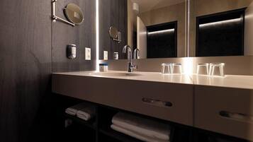 Un baño moderno con un espejo grande, un lavamanos y un perchero para toallas.