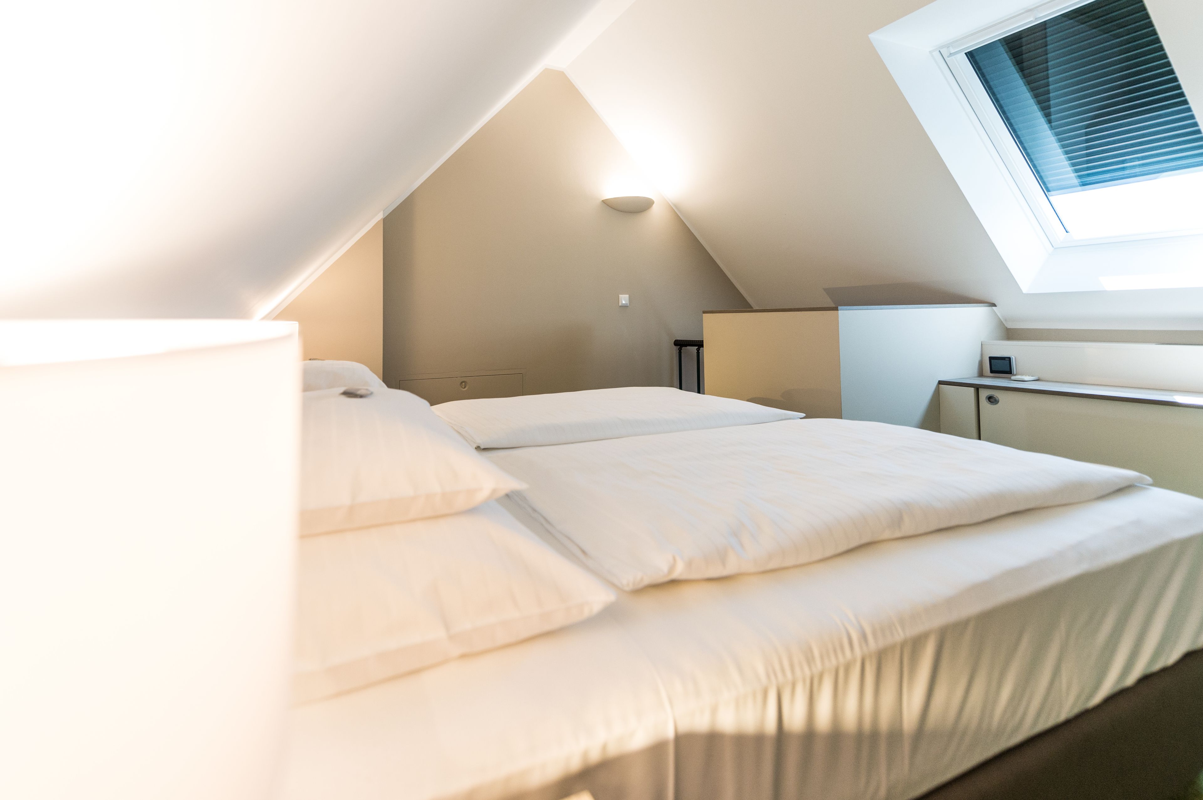 A bedroom with a bed, a desk, and a window.